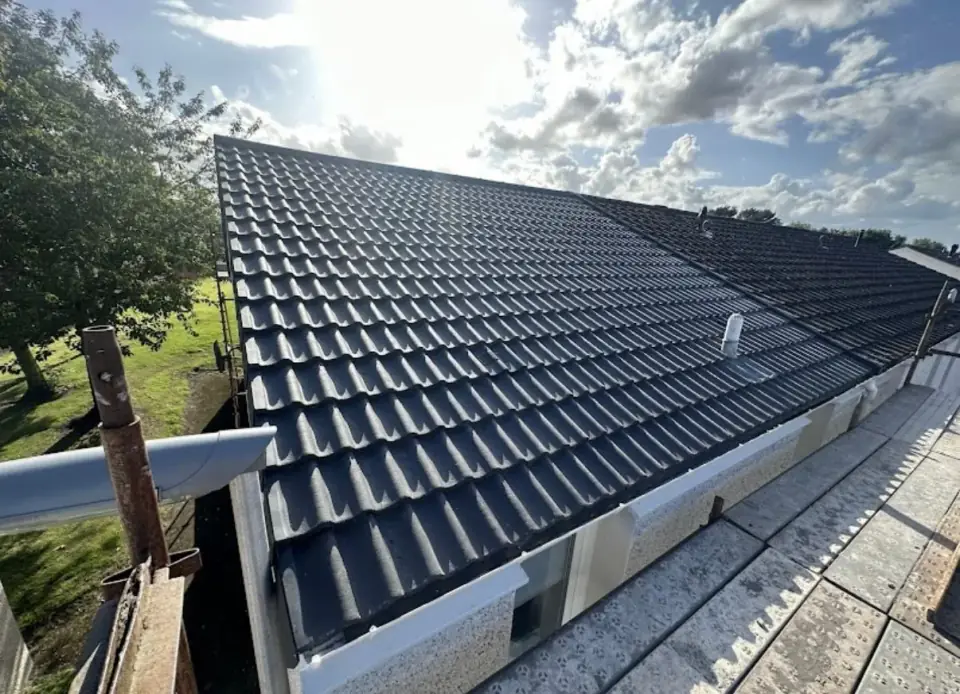 New roof in black interlocking tiles on a bungalow, with new white fascias